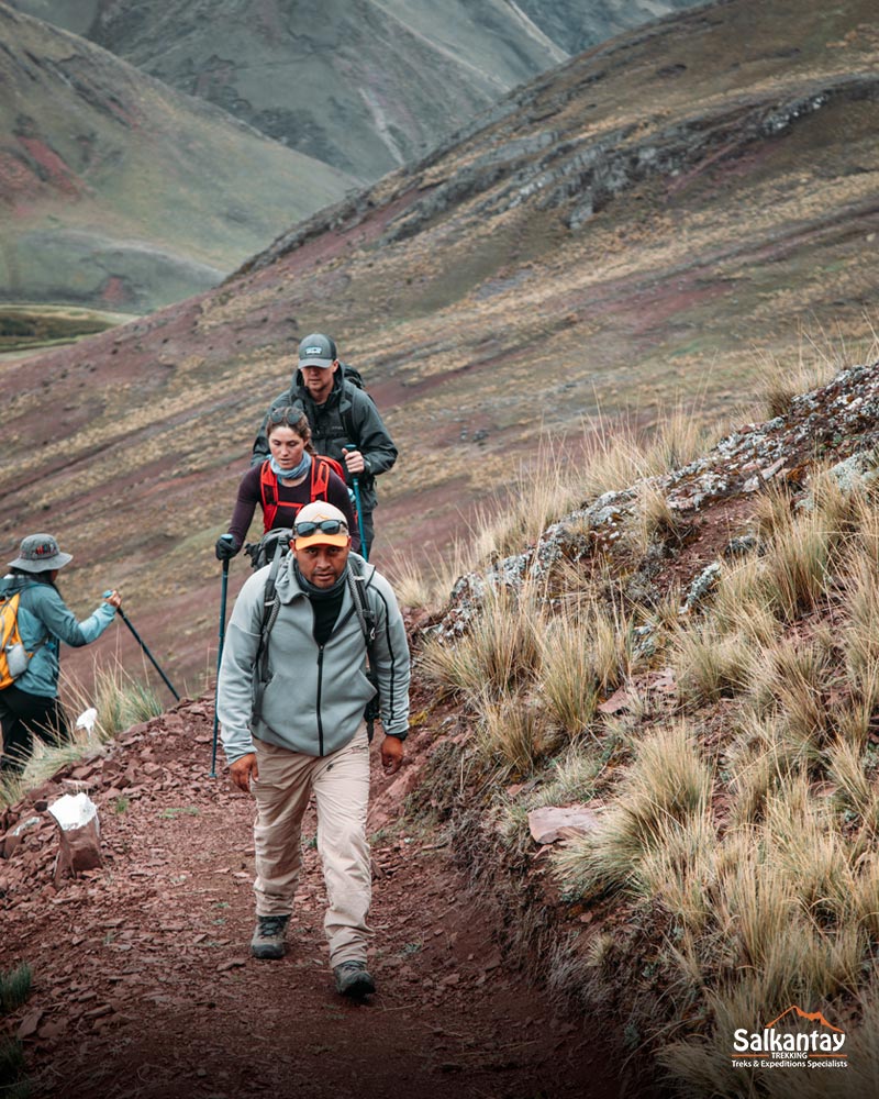 Turistas e seu guia caminhando até a montanha colorida de Pallay Punchu