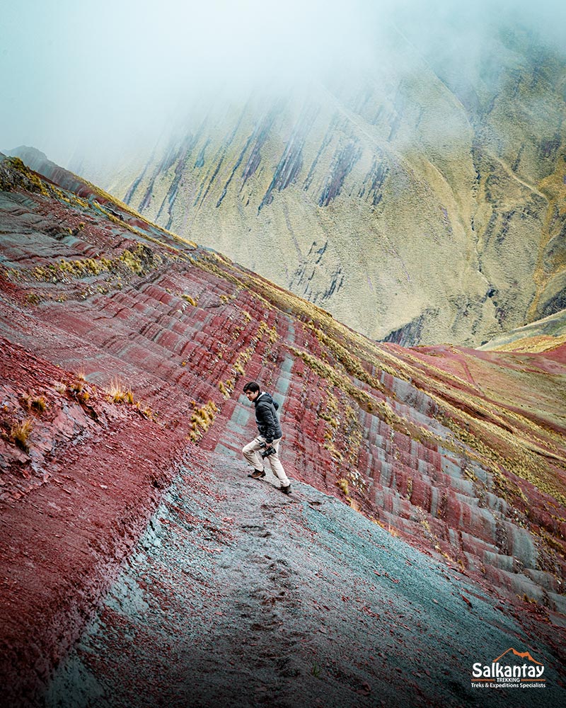 Turista caminhando pela montanha de cores de Pallay Punchu, uma maravilha natural.