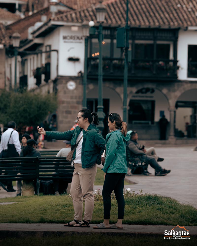 Dois turistas tirando uma selfie na praça principal da cidade de Cusco.