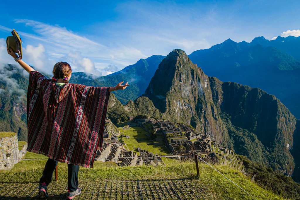 Turista com poncho andino no sítio arqueológico de Machu Picchu